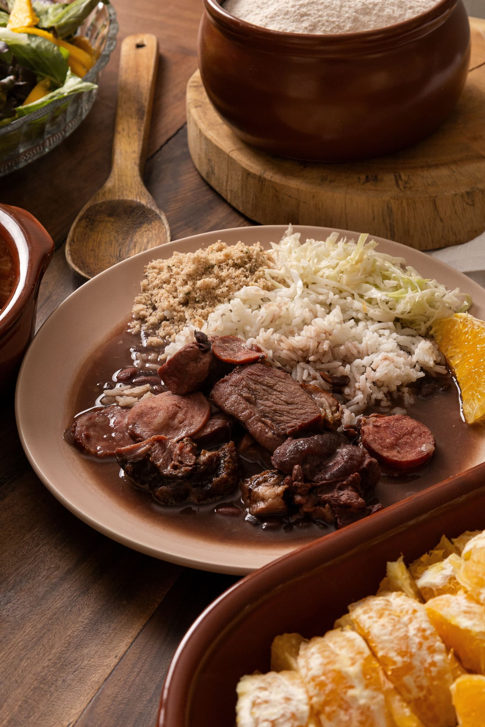 Feijoada servida com arroz, farofa, couve e laranja