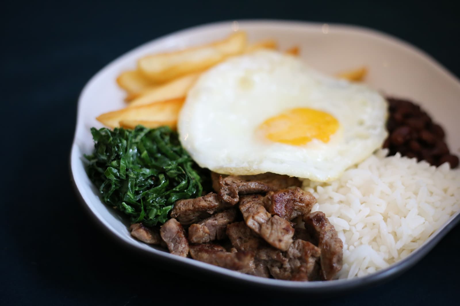 Prato feito com carne acebolada, ovo frito, couve, arroz, feijão e batata frita